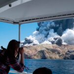 A man taking a picture from a boat of the white island volcanao eruption