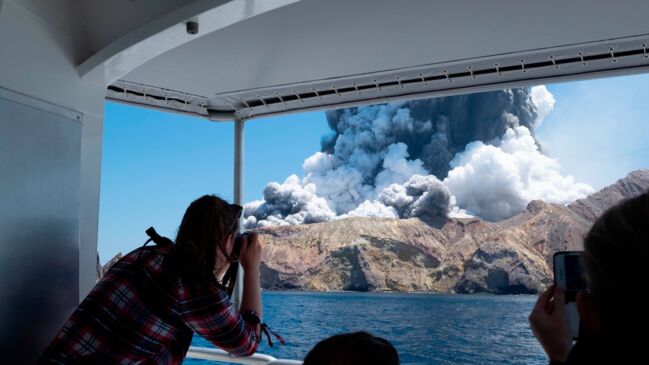 A man taking a picture from a boat of the white island volcanao eruption